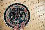 Stylized vines and blossoms in sapphire, rose, and green on a vintage round Art Deco rug.
