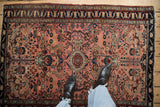 Vintage Lilihan rug with dusty rose field, playful floral arabesques, and dark navy patterned border.