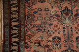 Vintage Lilihan rug, dark navy border, blush field with playful floral motifs, tattered fringe.
