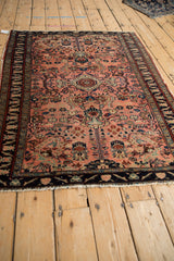 Vintage Lilihan rug corner revealing floral arabesques on a dusty rose field with navy border.