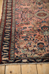 Vintage Lilihan rug's dark navy border alongside pale blush field with worn floral motifs.