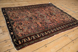Tattered edge of a vintage Lilihan rug showing the dark navy border with floral motifs.