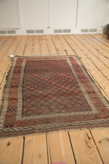 Antique Belouch rug with geometric diamond flowers, interlaced vines, and visible pile wear.