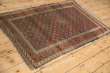 Geometric diamond patterns, lattice vines, and wear across knot heads on antique Belouch rug.