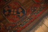 Vintage Beshir rug with red and navy gul, abrashed brown field, and fringed end.