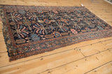 Corner of antique Mehriban rug, detailing navy plant motifs and dusty blush serpent border.