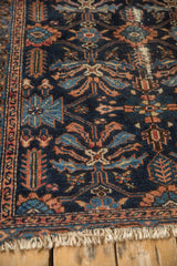 Close-up of antique Mehriban rug's worn serpent border and tattered ivory fringe.