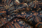 Close-up of germinating plant and serpent border motifs on a navy antique Mehriban rug.