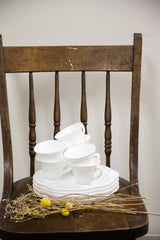Stacked white milk glass plates and cups with an embossed grapevine pattern.