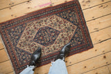 Corner of antique Senneh rug, featuring tight knotting and intricate Herati pattern with fringe.
