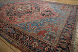Vintage Heriz carpet corner showing blush field, navy border, geometric motifs, and pile wear.