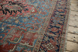 Heriz carpet: blush, navy, sky blue motifs, with worn pile showing foundation.