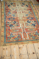 Antique Caucasian rug fragment showing geometric guls, hook and latch border, and visible wear.