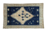 Distressed Oushak rug with a large stepped medallion in dusty cream against a rich cobalt blue field.