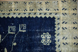 Distressed Oushak rug corner showing worn low pile on cobalt blue and pale gold motifs.