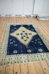 An angled view of the distressed vintage Oushak rug, highlighting the abrashed cobalt blue and cream design.