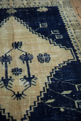 The distressed texture of a vintage Oushak rug's cobalt blue stepped spandrel and gold field.