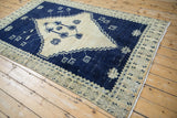Full angled view of a distressed Oushak rug with its bold cobalt blue and dusty cream medallion.