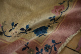 Textured pile of a vintage Art Deco rug, highlighting dusty pink border and blue vine motifs on ivory.