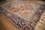 Vintage Heriz carpet, brick red field, navy Samovar border, abrashes, wear, and tattered edges.