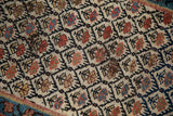 Close-up of antique Kurdish rug's hand-knotted trellis, ivory, navy, rust, and blue plants.