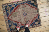 Geometric Caucasian rug with worn beige central medallion and primitive floral motifs, early 20th century.