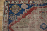 Primitive floral pinwheel motifs on cobalt blue field, with stepped red patterns and foundation wear.