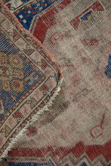 Folded edge of antique Caucasian rug, revealing worn pile texture and tight hand-knotted foundation.