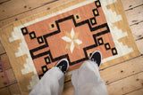 Textured vintage Navajo rug with dusty coral, ivory, and gold geometric stepped patterns.