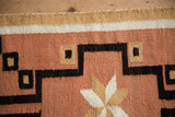 Vintage Navajo rug detail: hand-woven wool with coral, gold, brown geometric pattern.