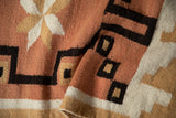 Soft, blanket-like wool texture with dusty coral, brown, ivory geometric stepped design.