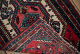 Folded corner of a vintage Hamadan rug showing its hand-knotted foundation and colorful wool pile.