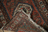 Tattered cream fringe and folded edge detail of vintage Hamadan rug, showing geometric patterns.