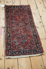 Angled view of a vintage Lilihan rug mat highlighting its worn floral pile and plain weave end.