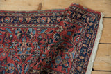 Folded corner of a vintage Lilihan rug revealing the pile texture and worn plain weave foundation.