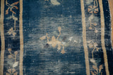 Antique Chinese Peking rug: worn cobalt blue field, faded ivory florals, extensive foundation showing.