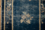 Antique Peking rug detail: cobalt blue field, beige border, floral spray with visible wear.