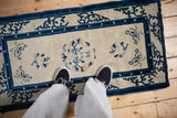 Antique Peking runner's ivory field featuring dense cobalt blue curvilinear designs and time-softened pile.