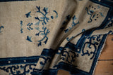 Deep cobalt blue curvilinear border of a folded antique Peking rug runner.