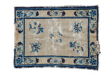 Antique Peking rug: ivory field, blue florals, cobalt lotus border, visible wear.