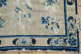 Antique Peking rug corner detail: cobalt blue lotus border, ivory field, and authentic storied wear.