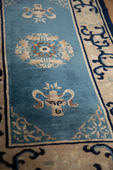 Stylized vase and intricate floral roundel on dusty blue Peking rug with arabesque border.