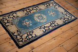 Antique Peking rug corner with dusty blue field, beige border, and dark blue arabesque motifs.