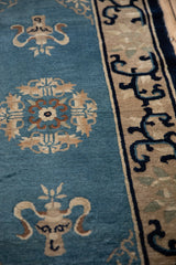 Dusty blue field with stylized vase motifs and the antique Peking rug's arabesque border.