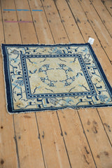 Upper corner of antique Peking rug, geometric cobalt blue border, cream field, frayed fringe.
