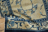 Folded antique Peking rug, showcasing textured cream, cobalt, and powder blue arabesques.
