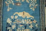 Pale saffron bat, floral motifs, geometric border on blue field, with wear.