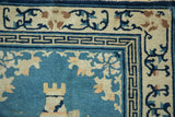 Antique Peking rug corner with geometric Greek key border and worn sky blue pile.