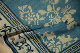 Antique Peking rug showing geometric border, sky blue field, and floral patterns.