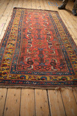 Angled view of an antique Kurdish Bijar rug with a ruby-red field and geometric Herati design.